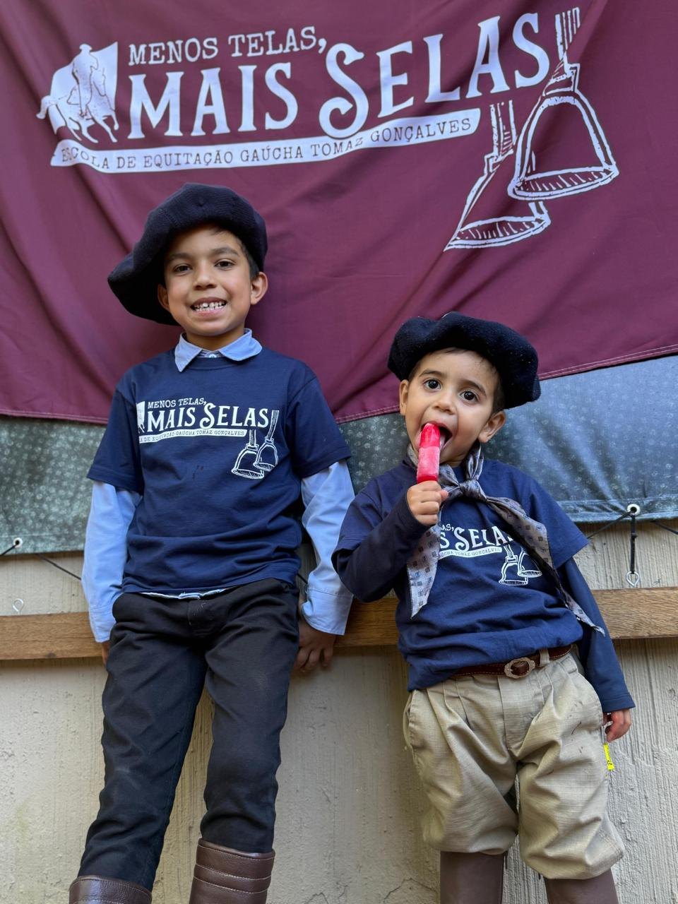 Duas crianças sorrindo com roupas do Menos Telas Mais Selas